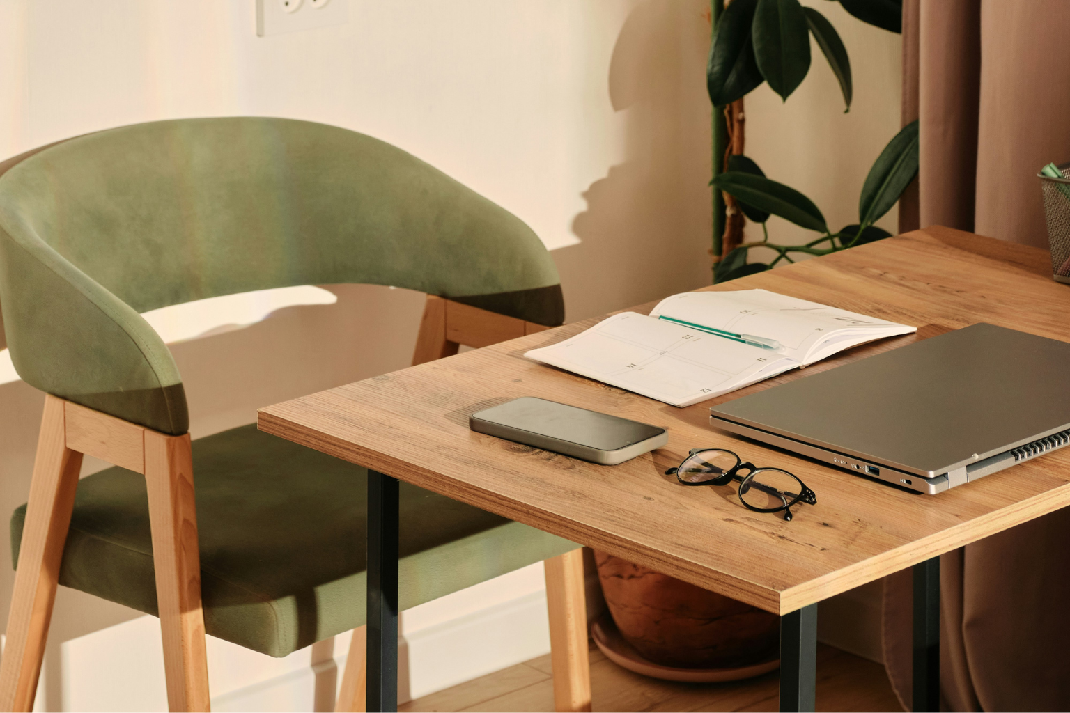 Sunlit workspace with an open planner, laptop and phone